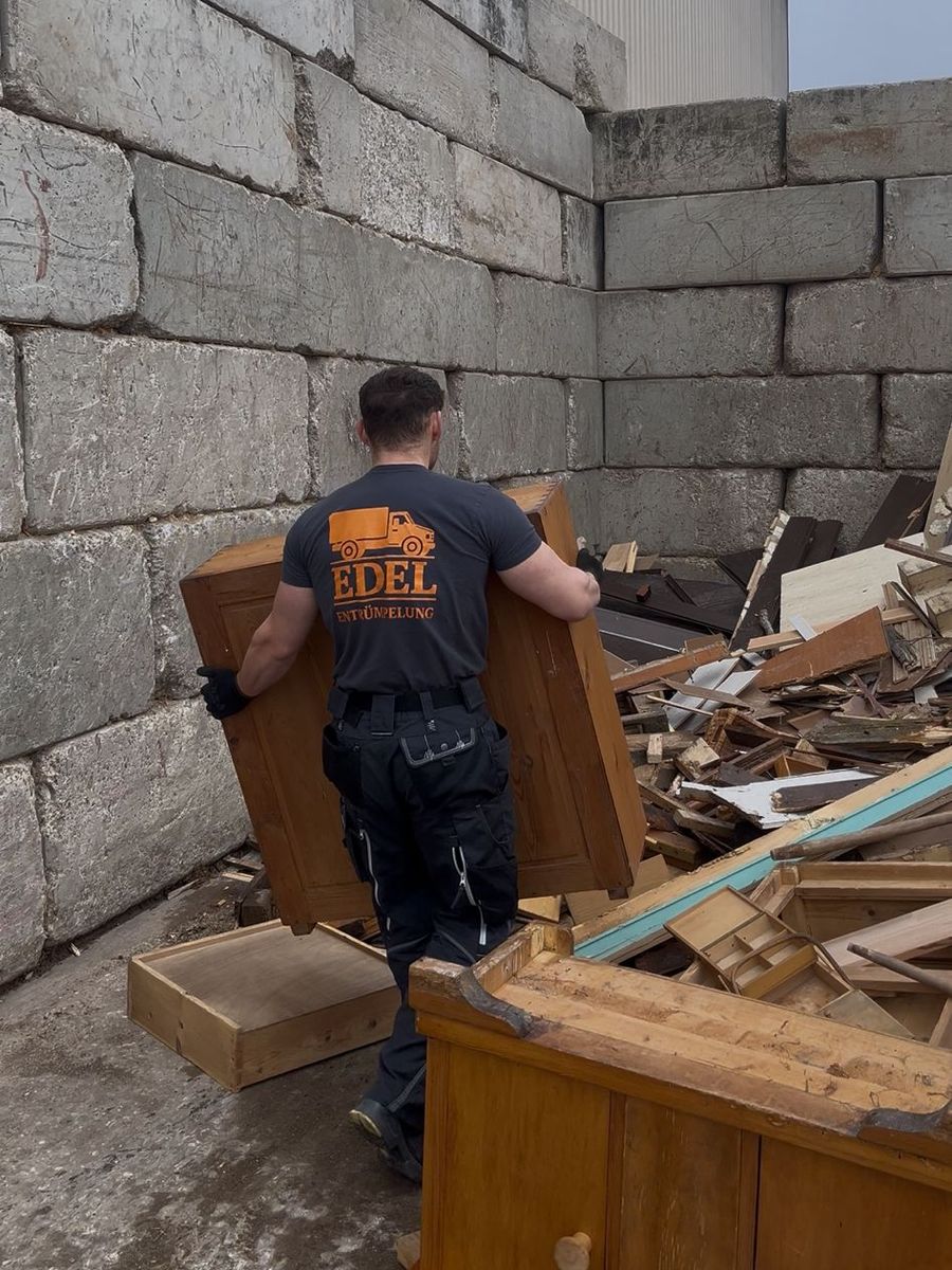 Mitarbeiter von Edel Entrümpelung Ansbach trägt einen Holzschrank zur fachgerechten Entsorgung